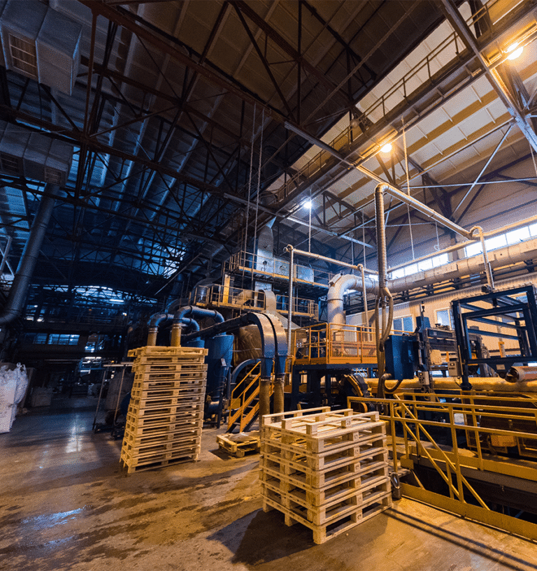 Stacked pallets and machinery inside a modern industrial factory