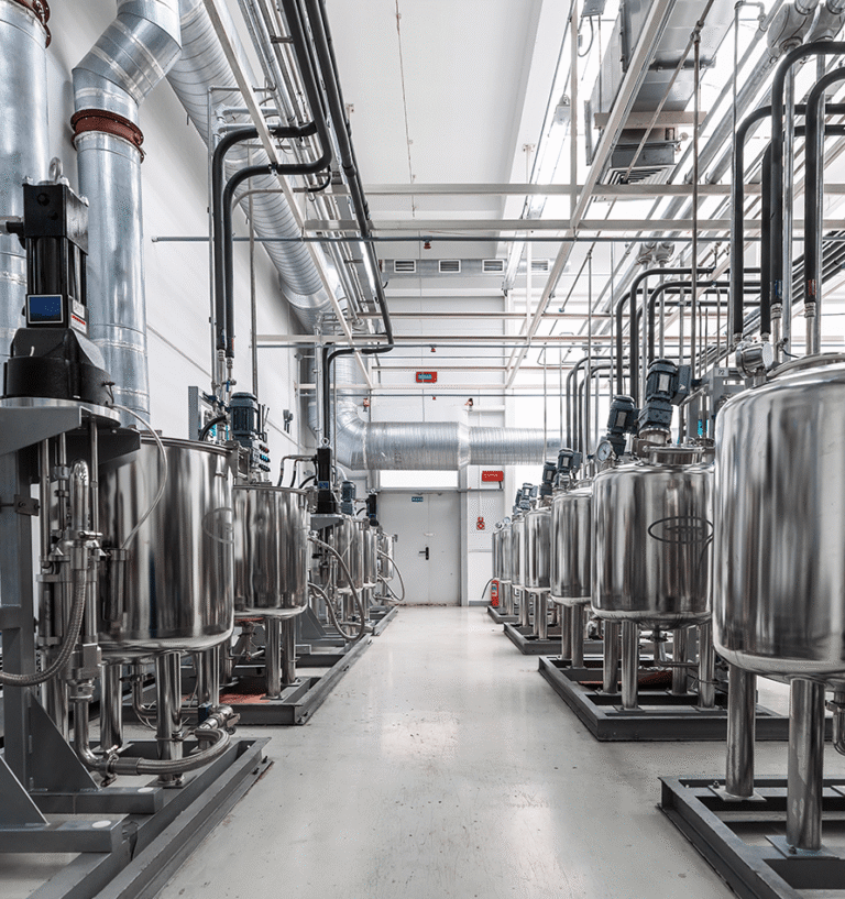Long corridor lined with stainless steel processing tanks and pipework in a clean facility