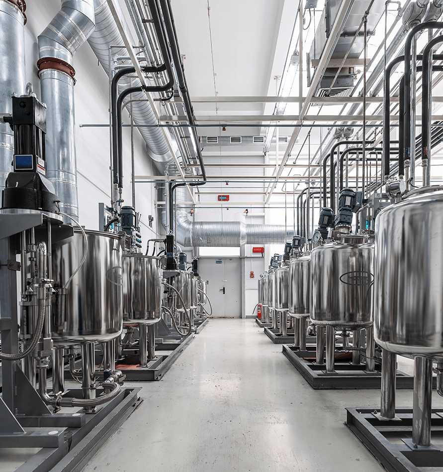 Long corridor lined with stainless steel processing tanks and pipework in a clean facility